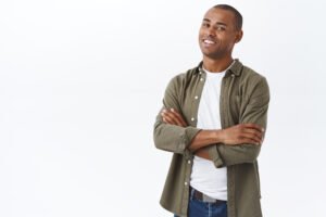 Portrait of smart, professional african-american man, standing white background with hands crossed on chest, confident pose, smiling satisfied, promote company service, delivery or customer support.